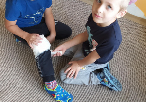 chłopiec zawija kolano bandażem